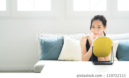 A woman doing skin care in the mirror indoors 119722111