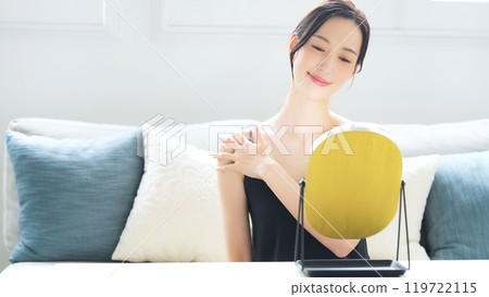 A woman doing skin care in the mirror indoors A woman doing skin care in the mirror indoors 119722115