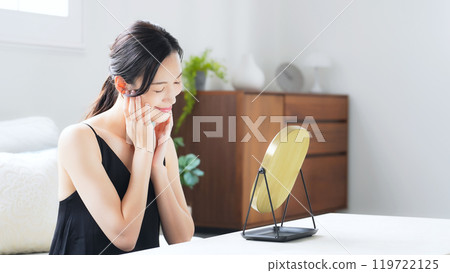 一個女人在室內照鏡子做皮膚護理 119722125