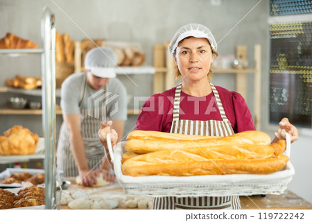 Adult woman baker with basket of baguettes 119722242