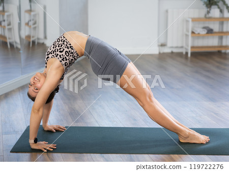 Young woman practicing yoga in urdhva dhanurasana pose 119722276