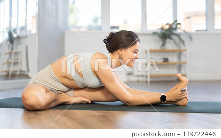 Portrait of young sporty woman making stretching legs and yoga pose at sports club Portrait of young sporty woman making stretching legs and yoga pose at sports club 119722446