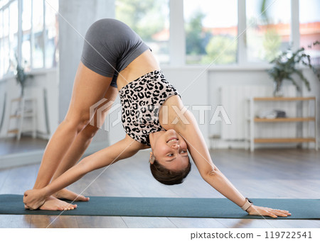 Athletic girl meditates in yoga pose parshvottanasana in the gym. Demonstration of various yoga poses 119722541