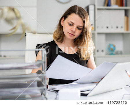 Woman bookkeeper doing paperwork in office 119722550