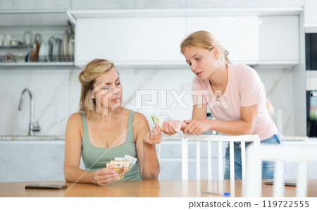 Mother gives teenage daughter bills small amount of pocket money. 119722555