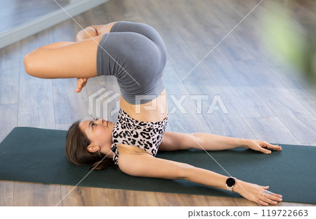Sporty young woman performing advanced yoga posture in studio 119722663