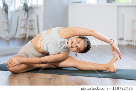 Young woman doing stretching Parivrtta Janu Sirsasana asana Young woman doing stretching Parivrtta Janu Sirsasana asana 119722756