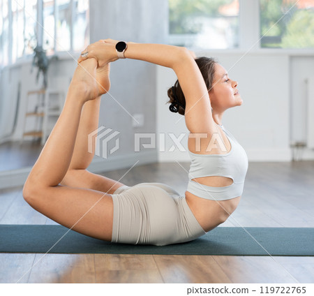 Young woman doing back bending asana Dhanurasana Young woman doing back bending asana Dhanurasana 119722765