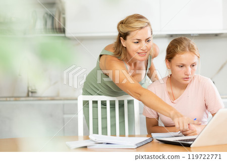 Woman offering assistance to teenage daughter studying at home Woman offering assistance to teenage daughter studying at home 119722771