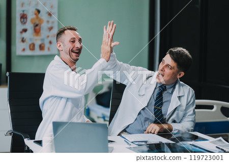 Smiling young male clinician shake hands with happy teammate appreciate for assistance on surgery show support respect on team council. Two doctors partners handshaking making deal reaching agreement 119723001