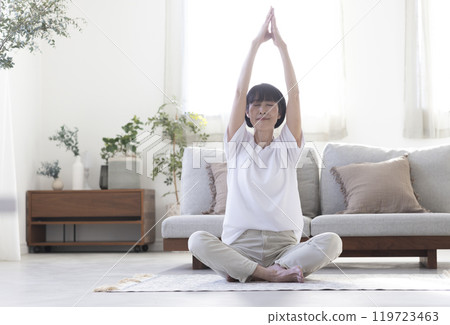Middle-aged woman doing yoga in her room 119723463
