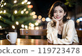 A woman posing with her chin resting on her hand in a cafe at night with beautiful illuminations 119723478