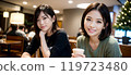 Two women relaxing in a cafe with a Christmas tree 119723480