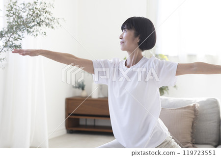 Middle-aged woman doing yoga in her room 119723551