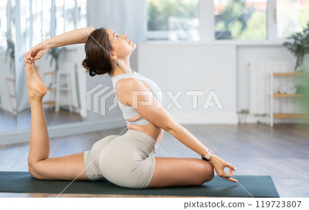 Positive sporty skilled young female teacher demonstrating table pose of yoga in training room 119723807