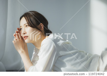 Young woman by the window Young woman by the window 119724042