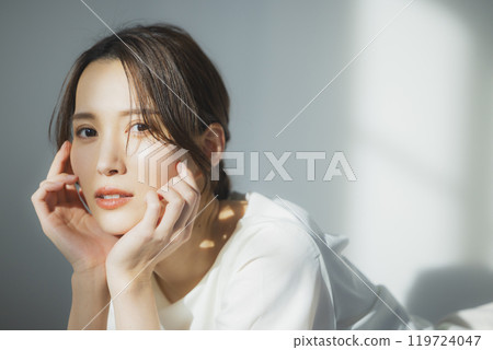 Young woman by the window Young woman by the window 119724047