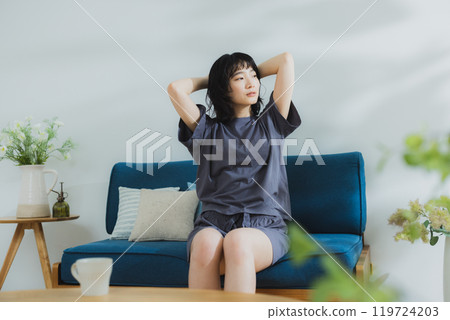 A young woman in loungewear stretching 119724203