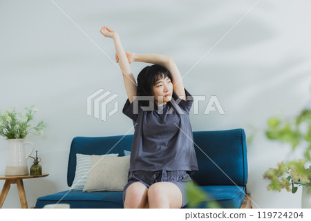 A young woman in loungewear stretching 119724204