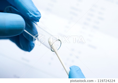 Doctor holds a COVID-19 swab collection, wears blue gloves and a PPE protective mask, and carries a test tube to collect the OP NP and  test coronavirus. 119724224