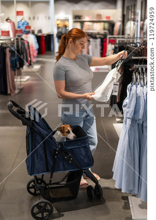 Caucasian woman shopping with her Jack Russell terrier dog in a stroller. Vertical photo.  119724959