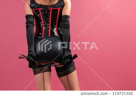 Beauty lady in a black latex dress holding the whip 119725388