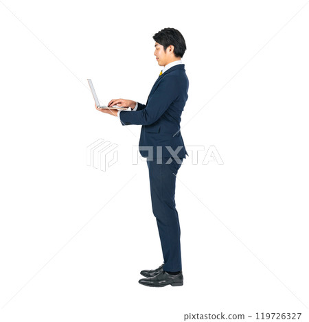 A young male business person using a laptop computer. A transparent full-body photo PNG precisely cut by hand 119726327