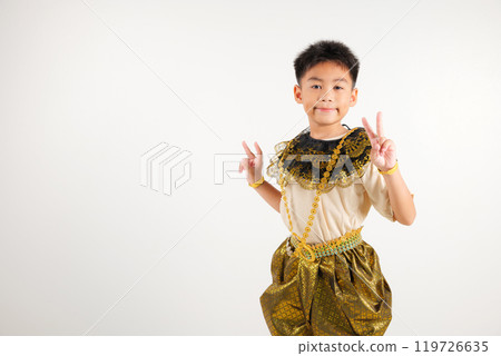 Portrait Thailand kid boy smiling traditional Thai dress costume radiates positivity by forming victory and peace signs, studio shot isolated white background, primary child V sign finger Portrait Thailand kid boy smiling traditional Thai dress costume radiates positivity by forming victory and peace signs, studio shot isolated white background, primary child V sign finger 119726635