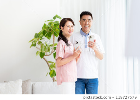 Senior couple looking at a smartphone in the living room 119727579