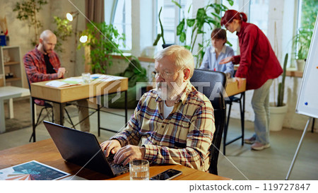 Senior man, leader sitting at desk with laptop, working in modern co-working space. Success planning 119727847