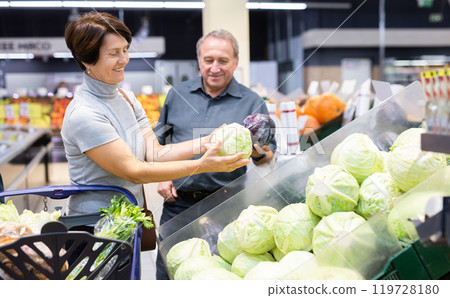 Husband and wife choose and buy fresh cabbage in grocery store 119728180