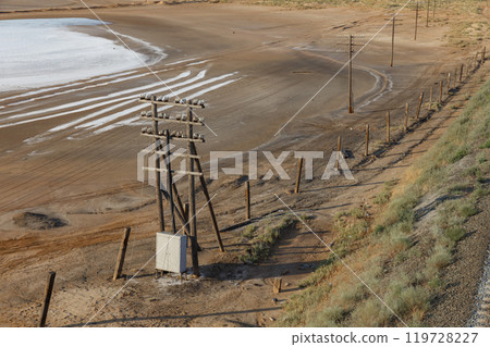 Overhead communication line on wooden supports along the railway near a salt lake. Kazakhstan Overhead communication line on wooden supports along the railway near a salt lake. Kazakhstan 119728227