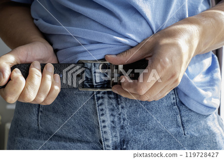 Hands unbuttoning leather belt on jeans Hands unbuttoning leather belt on jeans 119728427