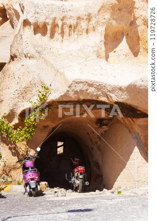 two rent scooters parked directly in front of a cave entrance in Cappadocia two rent scooters parked directly in front of a cave entrance in Cappadocia 119728726