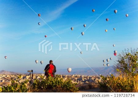 Photographer watch hot air balloons over a city in Cappadocia Photographer watch hot air balloons over a city in Cappadocia 119728734
