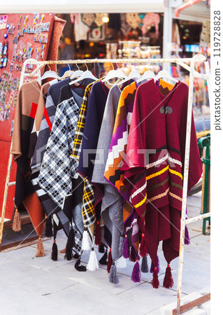A vibrant assortment of colorful clothes is hanging on a rack 119728828