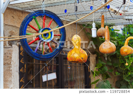 Colorful wooden wheel and pumpkin lantern adorned with ominous evil eyes hanging from it 119728854