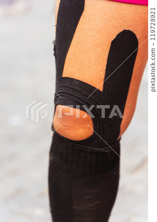 Athletic Tape Binding on the knees and legs with stockings on the girl's runner Marathoner Athletic Tape Binding on the knees and legs with stockings on the girl's runner Marathoner 119728921