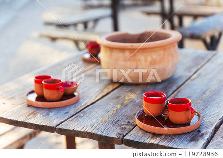 Rustic red clay coffee cups placed on a trays on a wooden table 119728936