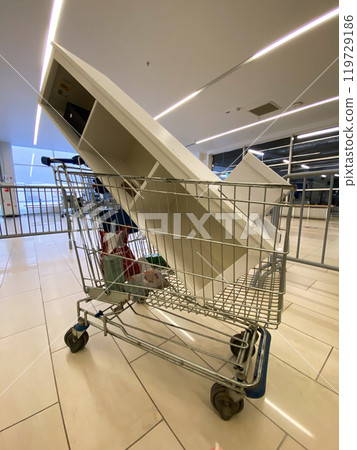 Large piece of furniture is precariously balanced in a shopping cart inside a spacious, modern mall. The unusual sight contrasts everyday shopping tasks with unexpected logistical challenges Large piece of furniture is precariously balanced in a shopping cart inside a spacious, modern mall. The unusual sight contrasts everyday shopping tasks with unexpected logistical challenges 119729186