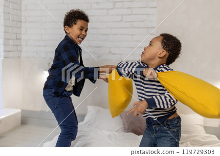 Two siblings having a pillow fight and looking excited Two siblings having a pillow fight and looking excited 119729303