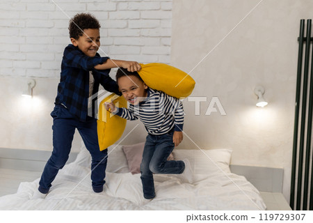 Two siblings having a pillow fight and looking excited Two siblings having a pillow fight and looking excited 119729307