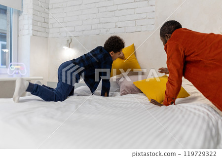 Father and son making bed in the morning together Father and son making bed in the morning together 119729322