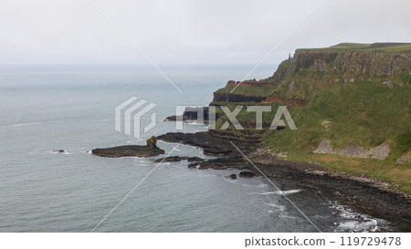 Giant Causeway rocky shore layered basalt cliffs calm Atlantic cloudy sky serene view 119729478