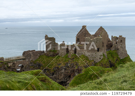 Dunluce Castle ruins on cliff overlook ocean rugged coast cloudy sky dramatic view 119729479
