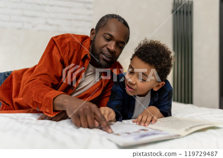 Dark-skinned man looking at the pictures in the boom together with his son 119729487