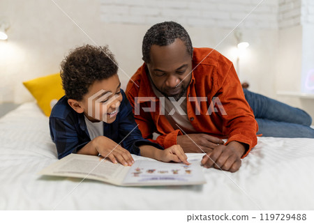 Dark-skinned man looking at the pictures in the boom together with his son 119729488