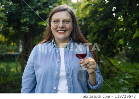Laughing young woman outdoors holding glass drinking wine in the countryside at the picnic. High quality photo. Laughing young woman outdoors holding glass drinking wine in the countryside at the picnic. High quality photo. 119729678