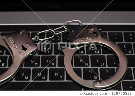 Handcuff and computer. online fraud on the internet. Handcuff and computer. online fraud on the internet. 119730581