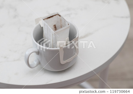 Cup with drip coffee bag on black table 119730664